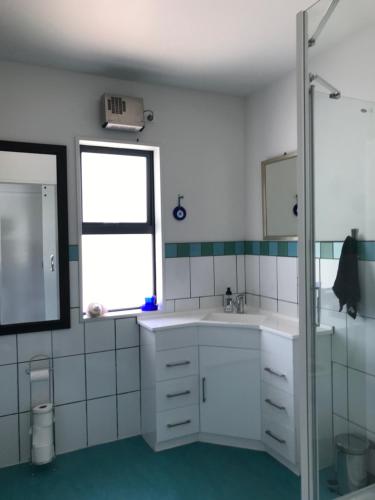 a white bathroom with a sink and a window at Woodbank Road Escape in Hanmer Springs