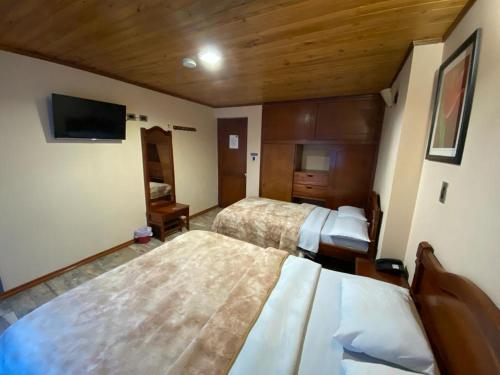 Habitación de hotel con 2 camas y TV de pantalla plana. en Hotel Buenaventura, en Pasto