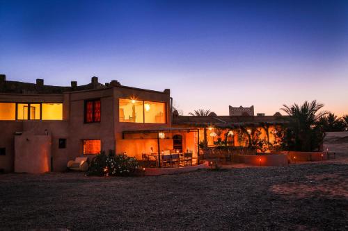 a large house with its lights on at dusk at Kasbah Mohayut in Merzouga