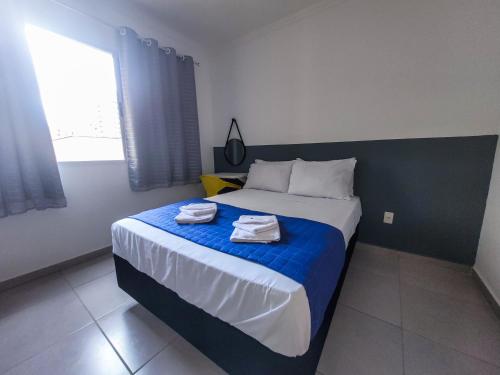 - une chambre avec un lit et 2 serviettes dans l'établissement Bem no CENTRO com cozinha completa, varanda e garagem, à Poços de Caldas