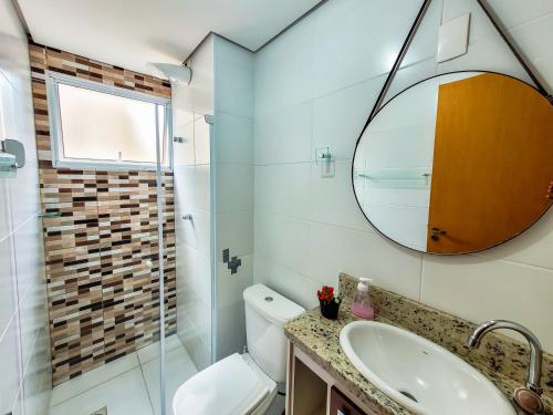 La salle de bains est pourvue de toilettes, d'un lavabo et d'un miroir. dans l'établissement Bem no CENTRO com cozinha completa, varanda e garagem, à Poços de Caldas