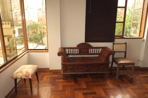 a bench and a chair in a room with windows at Inkawasi Miraflores Hostel in Lima