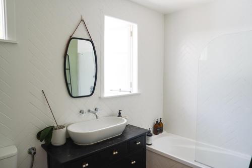 a white bathroom with a sink and a mirror at The Gallery in Havelock North in Havelock North