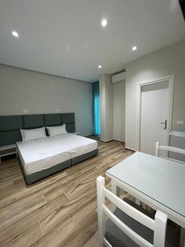 une chambre avec un lit, une table et des chaises dans l'établissement Hotel Rai, à Saranda