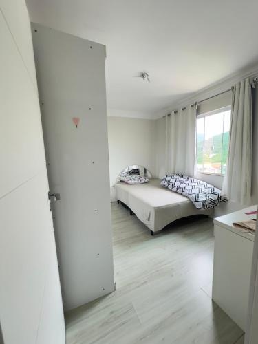 a bedroom with a bed and a large window at Quarto Individual in Camboriú