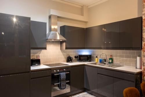 a kitchen with black cabinets and a stove top oven at Clarence House in Brighton & Hove