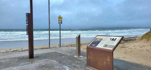 a sign next to a beach with the ocean at Brook Manor Lodge in Tralee