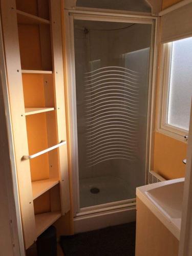 une douche en verre dans une salle de bain avec un lavabo dans l'établissement Mobil home, jacuzzi, vélos, barbecue et mer et plage à 300m, à Hyères
