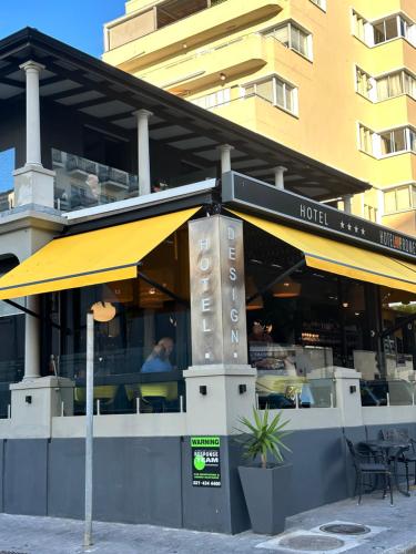 Hotel on the Promenade في كيب تاون: مطعم فيه مظله صفراء امام مبنى