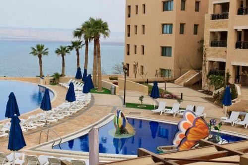 una piscina en un hotel con sillas y sombrillas en E13 Samarah Resort Apartment, en Sowayma