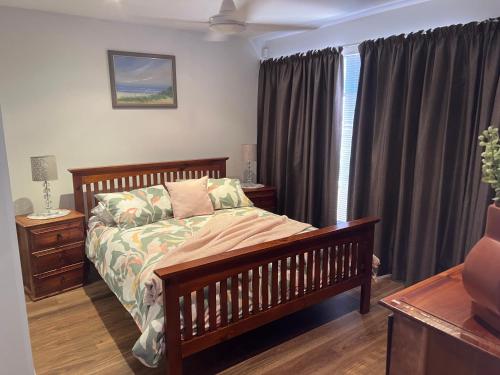 1 dormitorio con cama de madera y ventana en Victor Holidays en Victor Harbor