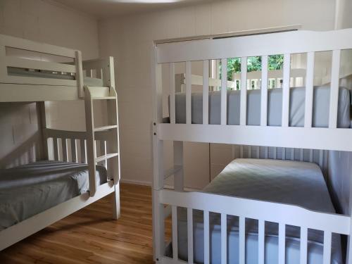 two white bunk beds in a room with wooden floors at Tasman Motor Camp in Tasman