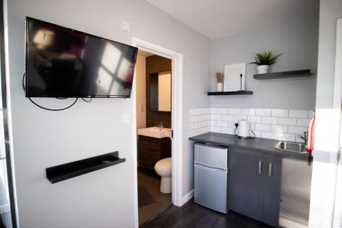een badkamer met een wastafel en een toilet en een tv aan de muur bij Dunstable Rd Modern Ensuites by Pioneer Living in Luton