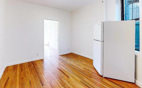 una stanza vuota con frigorifero bianco e pavimenti in legno di spaciou 1 Bedroom apartment in NYC! a New York