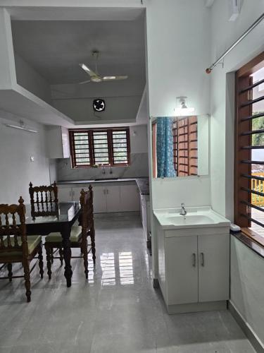 een keuken met een wastafel en een tafel en een tafel en een piano bij ZEAL HOMES And Apartments Koothattukulam in Kuttāttukulam