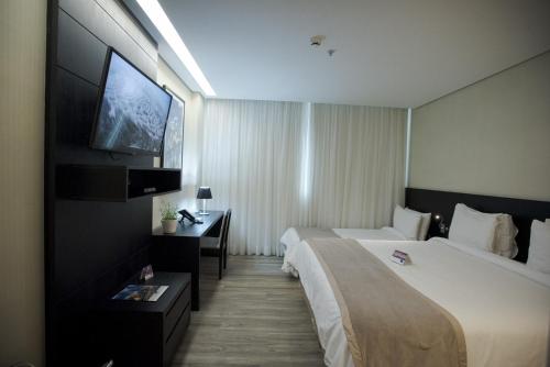 um quarto de hotel com duas camas e uma televisão de ecrã plano em Tryp by Wyndham Belo Horizonte Savassi em Belo Horizonte