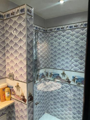 baño con ducha de cristal con azulejos azules en Pavillon Luxury, en Marrakech