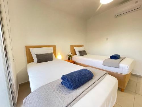 2 Betten in einem kleinen Zimmer mit blauem Handtuch in der Unterkunft Aurora Holiday Apartment - Ayia Napa in Ayia Napa