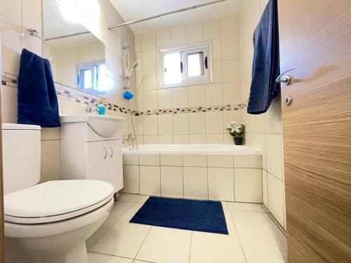 a bathroom with a toilet and a tub and a sink at Aurora Holiday Apartment - Ayia Napa in Ayia Napa