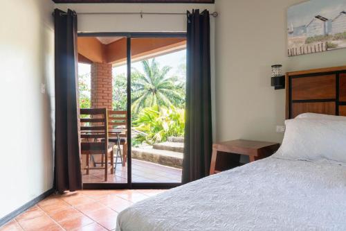 a bedroom with a bed and a view of a patio at Bongo - Adults Only in Manuel Antonio