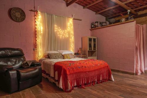 a bedroom with a bed with a red blanket and a chair at Cabañas Gonzalez in Salcoatitán