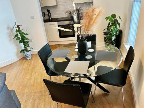 a glass table with black chairs and a vase with flowers at Home In The Heart Of Southsea in Portsmouth