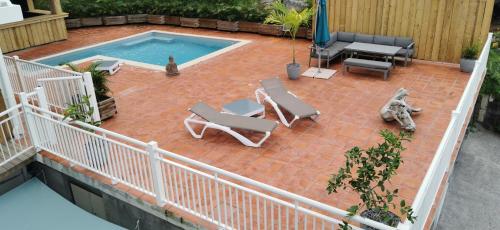a patio with two lounge chairs and a swimming pool at VILLA ELEM in Rivière-Pilote