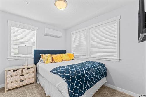 a bedroom with a bed with a blue blanket and two windows at Stay and Play in Luxury Coffey Villas in Garden City