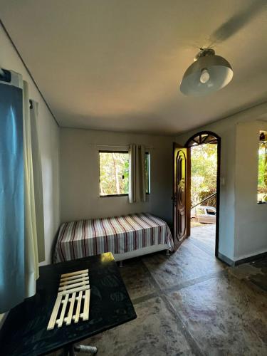 um quarto com uma cama, uma mesa e janelas em Casa Amarela Cipó Suítes e Cipó Kombi VIP 600m centro Serra do Cipó em Santana do Riacho