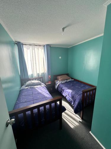 2 camas en una habitación con paredes azules en Frente a aeropuerto, en La Serena