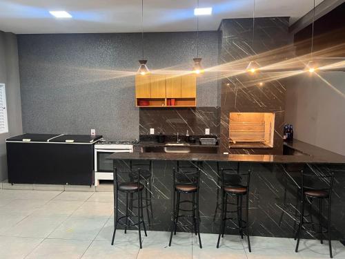uma cozinha com um balcão preto e bancos de bar em Área de lazer espaço Reis em Sao Jose do Rio Preto