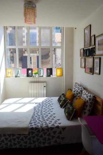 1 dormitorio con 1 cama grande en una habitación con ventanas en Logement cozy proche du centre-ville, en Poitiers