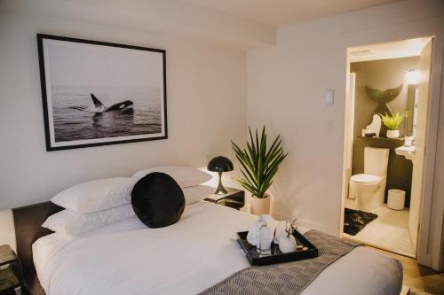 een slaapkamer met een wit bed met een foto aan de muur bij The Orca Pad at Waddigton Flats in Victoria