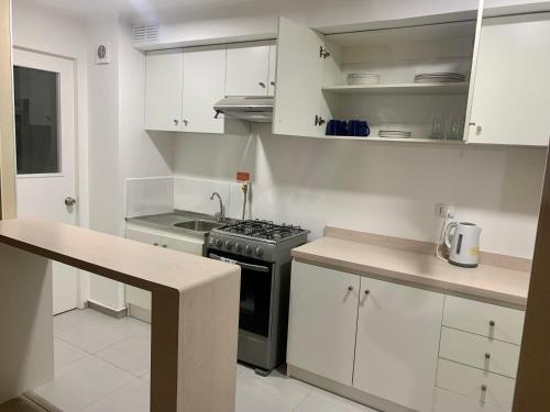 a kitchen with white cabinets and a stove top oven at Departamento nuevo con perfecta ubicación in Osorno