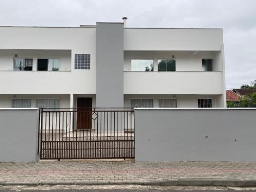 Biały budynek z bramą przed nim w obiekcie Apartamento Completo 2 Quartos com AC em Blumenau SC à 10min Vila Germânica, ideal para família, berço disponível! w mieście Blumenau