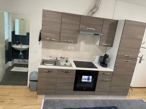 La cuisine est équipée de placards bruns et d'un évier. dans l'établissement Studio très agréable à Chessy, à Chessy