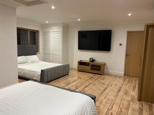 a bedroom with two beds and a flat screen tv at Broadway Pool House with Sauna & Jacuzzi in Herne Bay