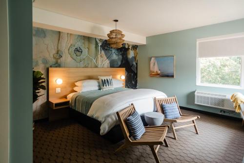 a bedroom with a large bed and two chairs at The Grove Motel in Colchester