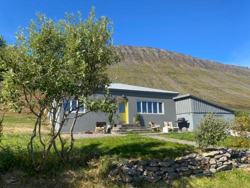 a house with a hill in the background at Sea, fjord & mountain view house in Súðavík