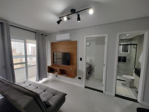 un salon avec un canapé et une télévision dans l'établissement Apto com lazer completo, piscina, ar, mercadinho e pet friendly a 1 min da praia, à Praia Grande