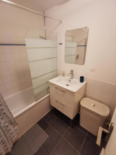 La salle de bains est pourvue d'un lavabo, d'un miroir et d'une baignoire. dans l'établissement L'Escale - Entre Mer et Marché, à Toulon