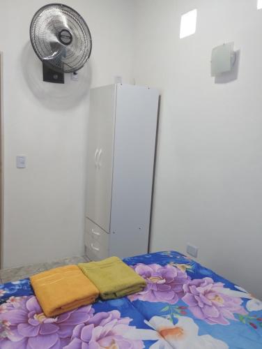 a room with a bed with two towels and a fan at Atardecer Serrano in Huerta Grande