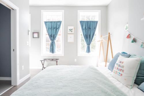 ein weißes Schlafzimmer mit blauen Vorhängen und einem Bett in der Unterkunft Neat Suites, The Baldwin Flatts in Covington