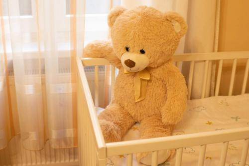 a brown teddy bear sitting in a crib at Apartmany u tri jehnatek in Karlovy Vary