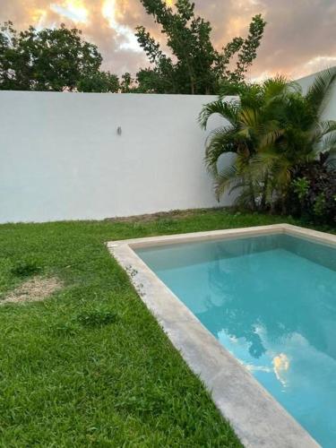 una piscina en el césped junto a una pared blanca en Residencia nueva en Merida, 