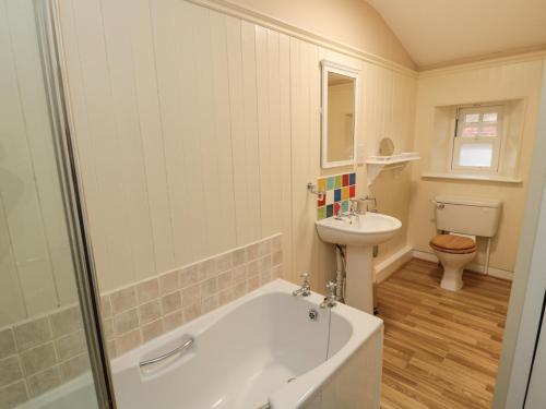 a bathroom with a tub and a sink and a toilet at Courtyard Cottage in Alnwick