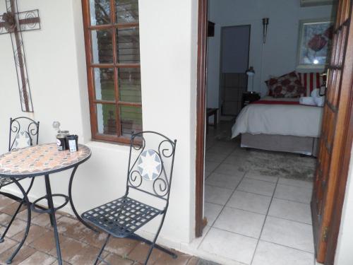 a table and chairs in a room with a bedroom at A Cherry Lane Self Catering and B&B in Bloemfontein