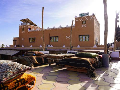 a building with tables and pillows on a patio at La Kasbah Elkhorbat Muxu Berbere in Asrir