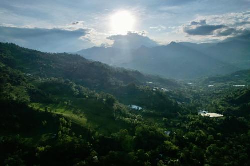 a view of a mountain valley with the sun in the sky at El Refugio del Oso de Anteojos in Fómeque