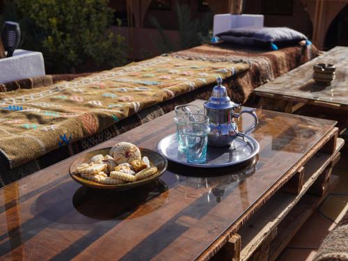 a coffee table with a bowl of cookies and a tea kettle at La Kasbah Elkhorbat Muxu Berbere in Asrir